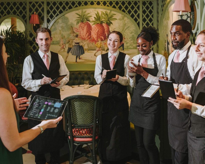 The image shows restaurant staff having a team briefing before the restaurant opening.