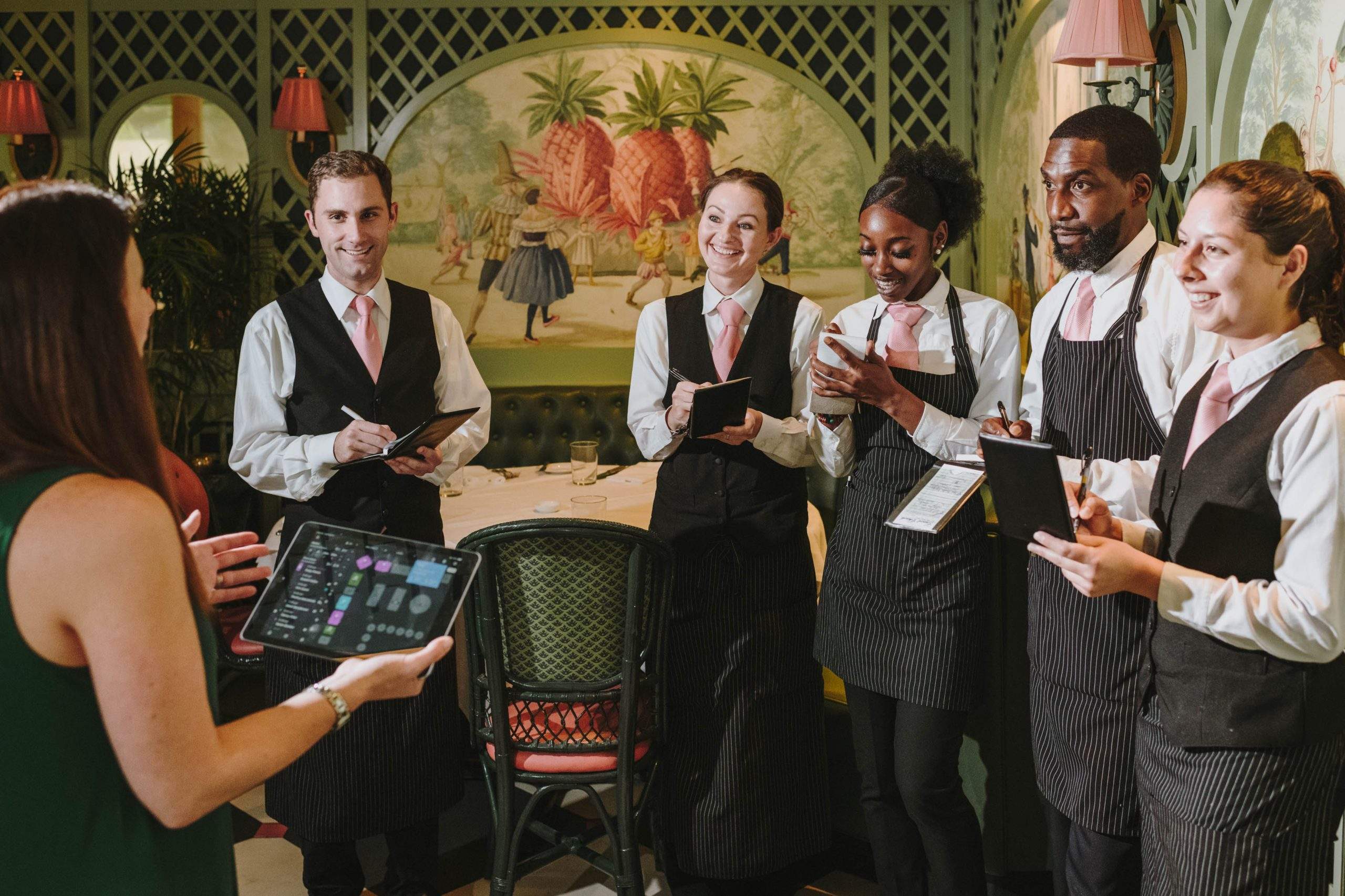 The image shows restaurant staff having a team briefing before the restaurant opening.