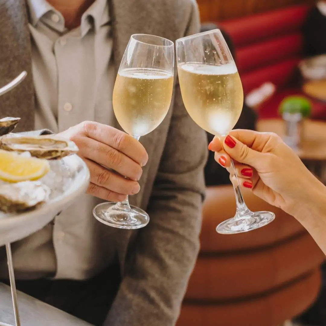 Two people cheering with champagne and oysters