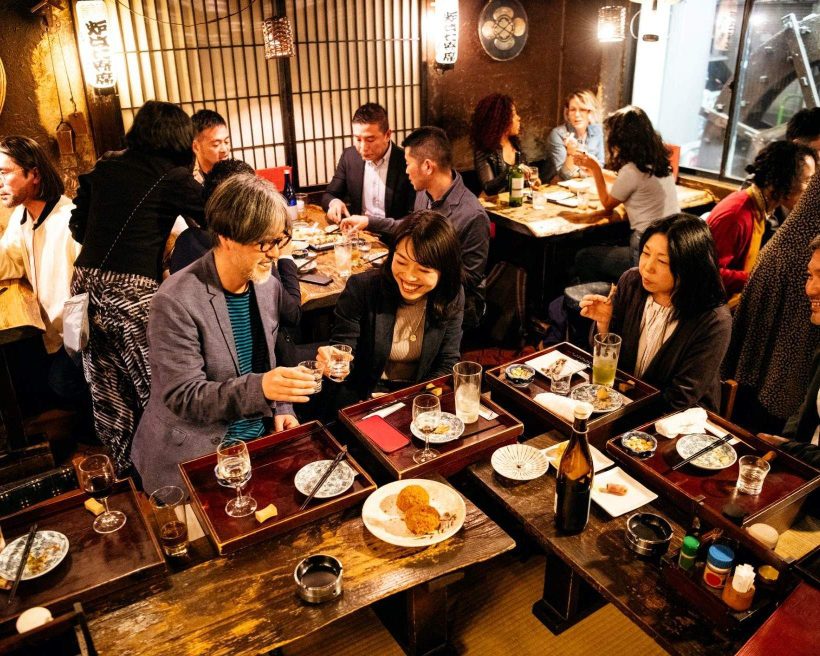 People dining and cheering in a lively Japanese restaurant