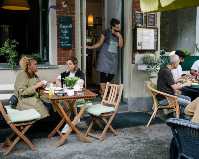 A waiter looks outside his restaurant, where people are having lunch and coffee in the outdoor restaurant courtyard.