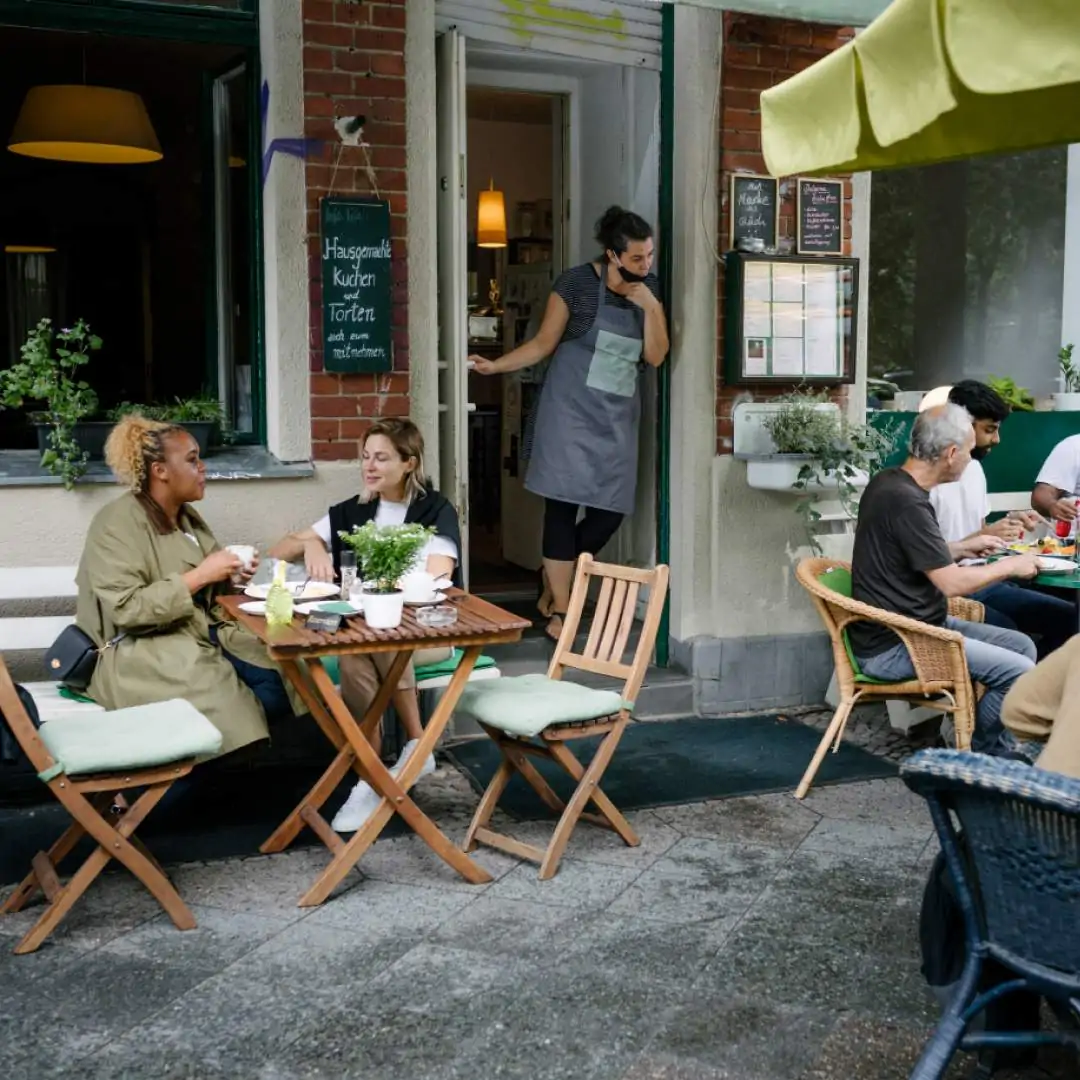 A waiter looks outside his restaurant, where people are having lunch and coffee in the outdoor restaurant courtyard.